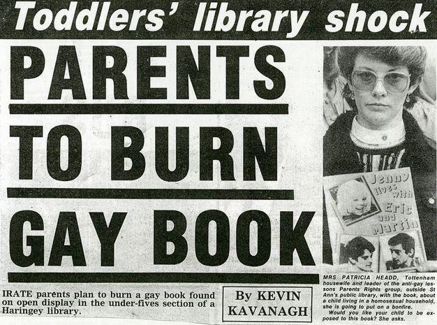 Newspaper clipping. An excerpt from a newspaper clipping has a headline that reads, “Toddlers’ library shock: PARENTS TO BURN GAY BOOK.” A subheading describes how “irate parents plan to burn gay book found… in the under-fives section of a Haringey library.” Included is an accompanying photograph of a woman holding a book entitled “Jenny Lives with Erin and Martin.” 